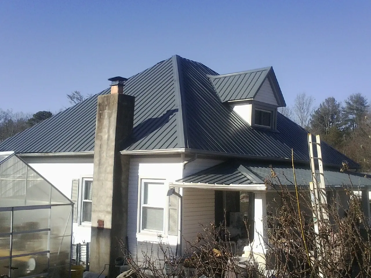 Dark blue standing seam metal roof on a white farmhouse with dormer — Slate & Tile Roof Repair by Roofing Brothers in Sullivan