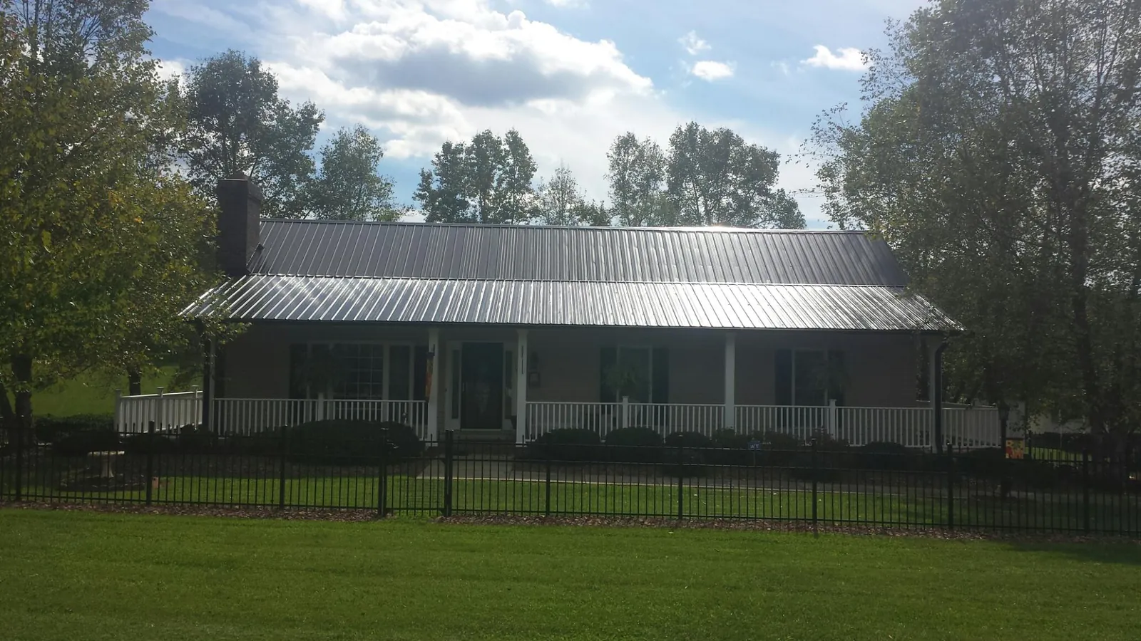 Gray metal roof on a brick ranch with a full width front porch — Gutter Guard Installation work by our crew in Sullivan